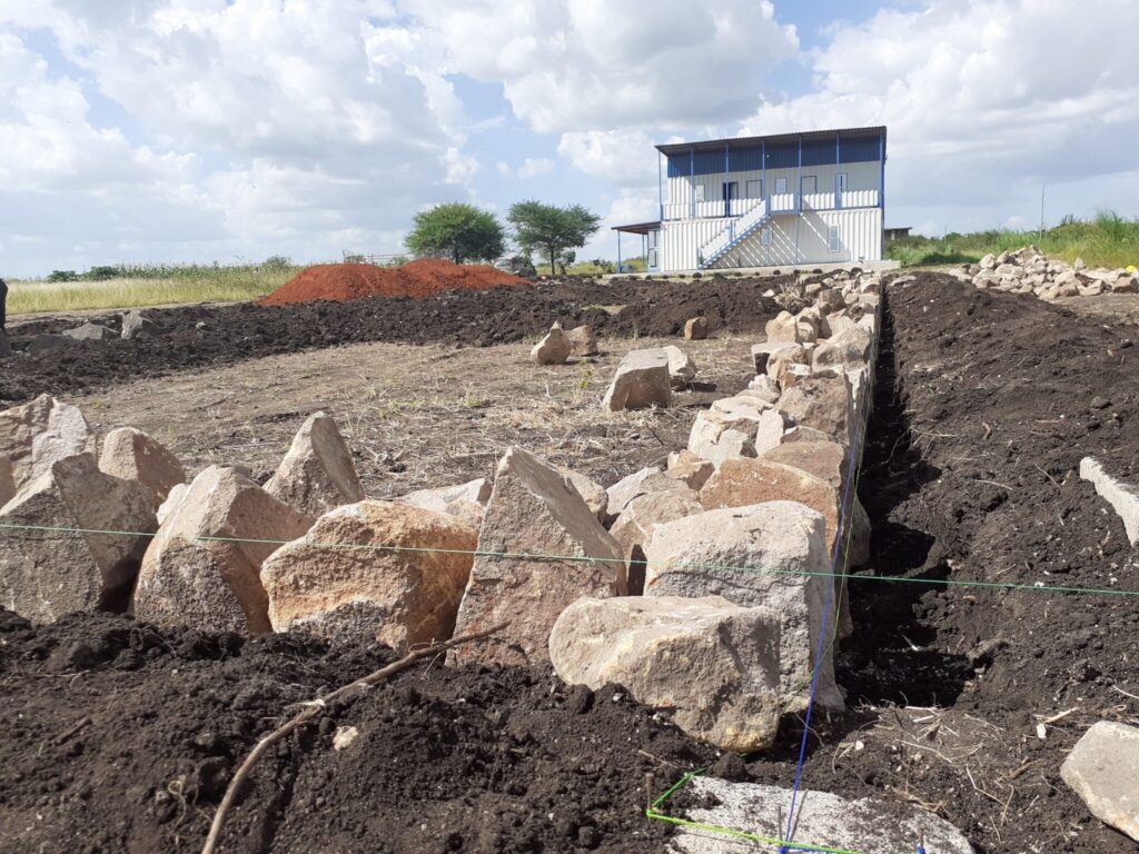 Partially built stone foundation with a building in the background.