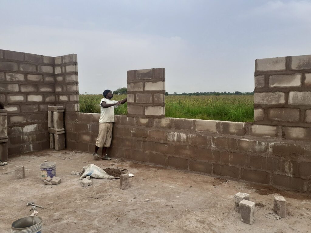 Man building a wall with cement blocks.