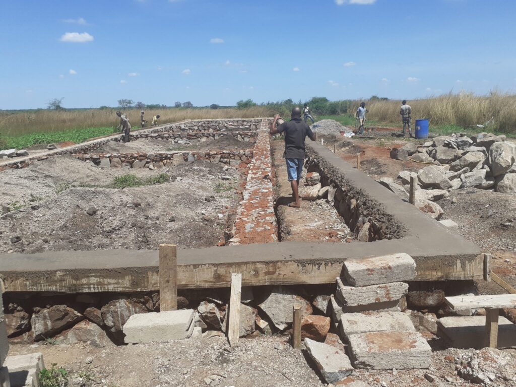 Workers at a construction site with stone walls.