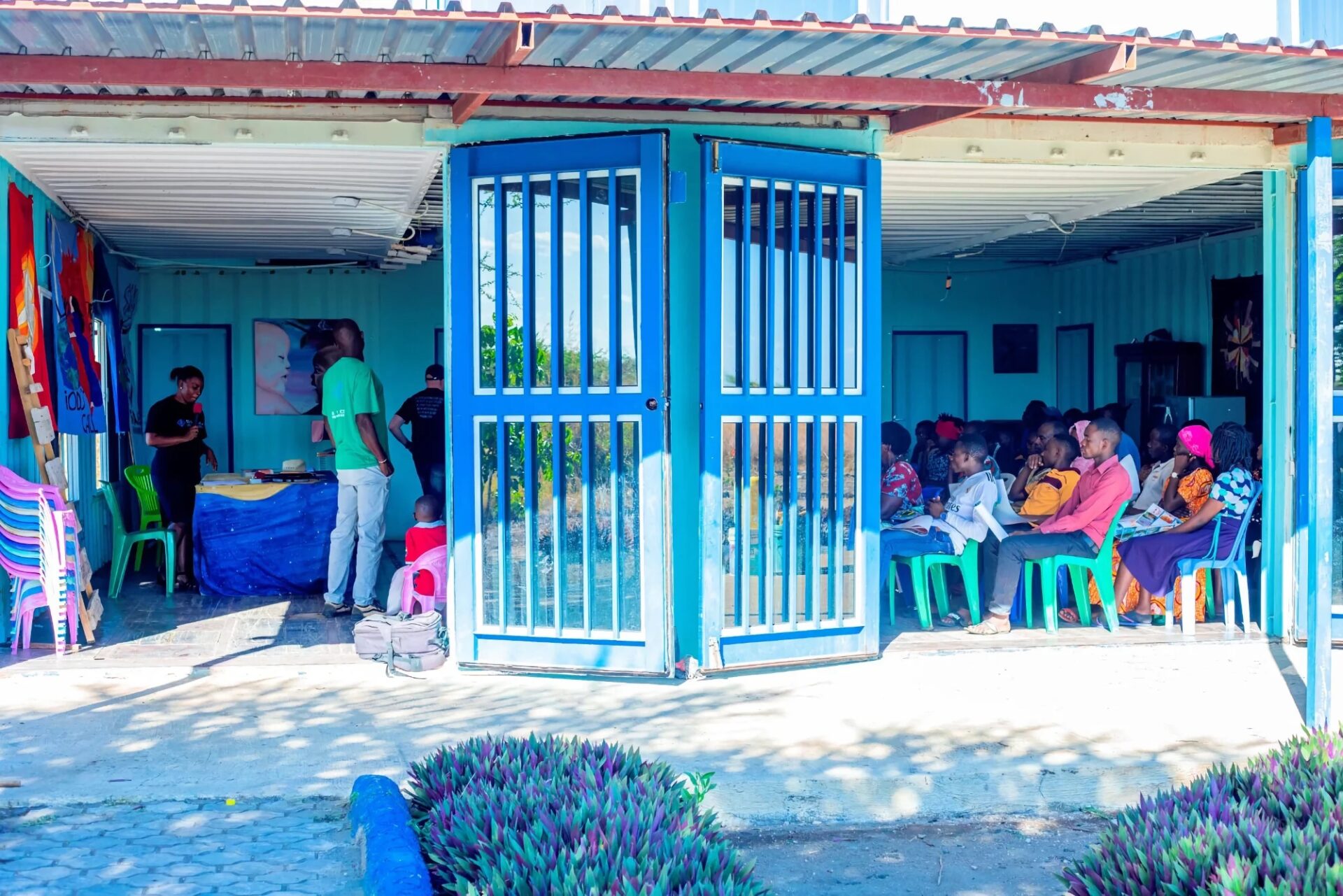 Community gathering inside a blue building with open doors.