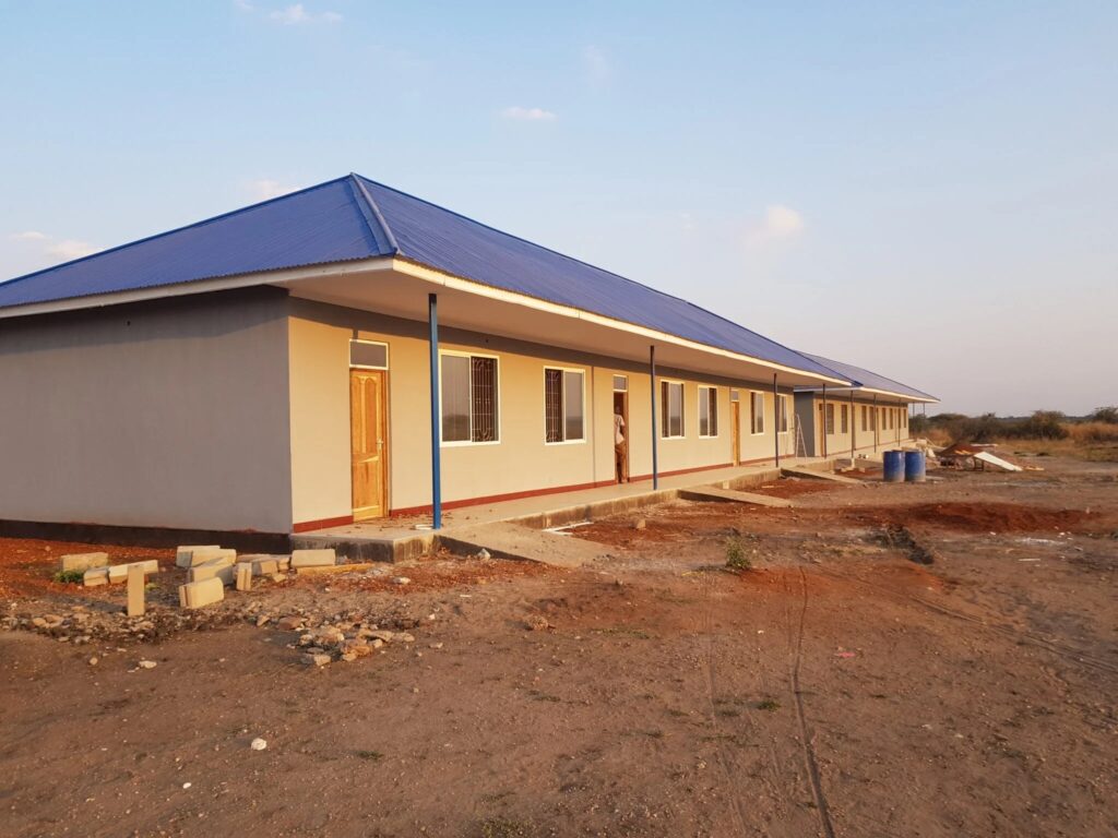 Long building with a blue roof and multiple doors.