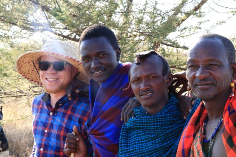 Group of people in traditional attire and a man wearing a hat.