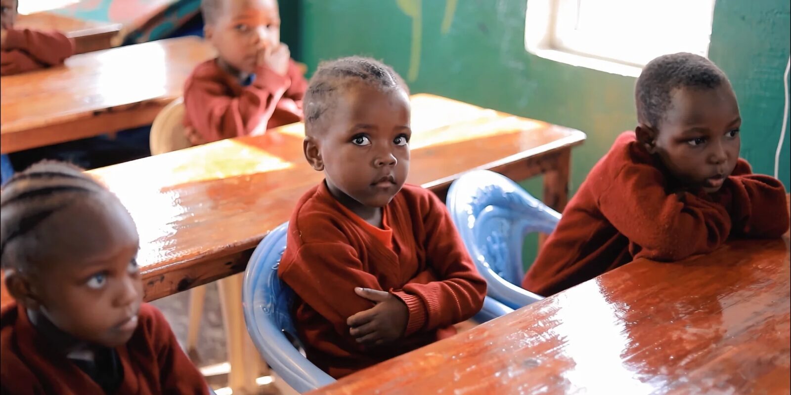 Children sitting at wooden desks in a classroom.