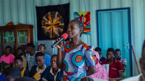 Woman speaking into a microphone in a community meeting.