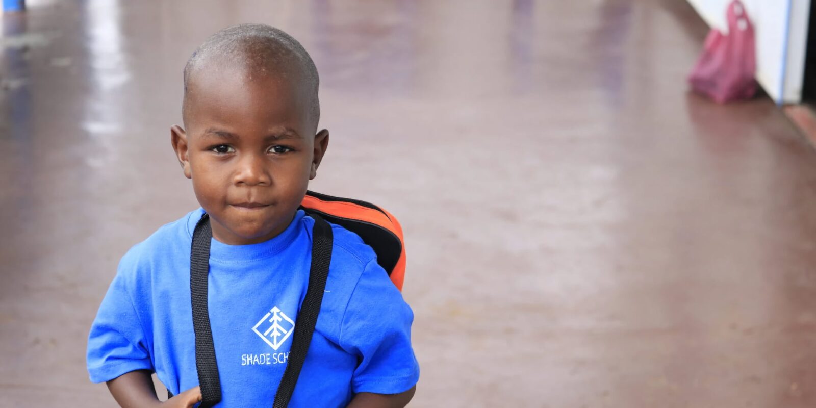 Boy in a blue shirt with a backpack.