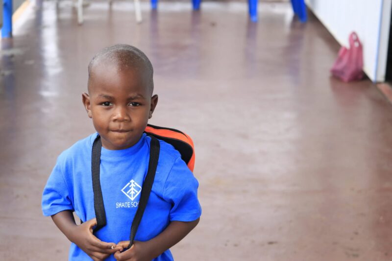 Boy in a blue shirt with a backpack.