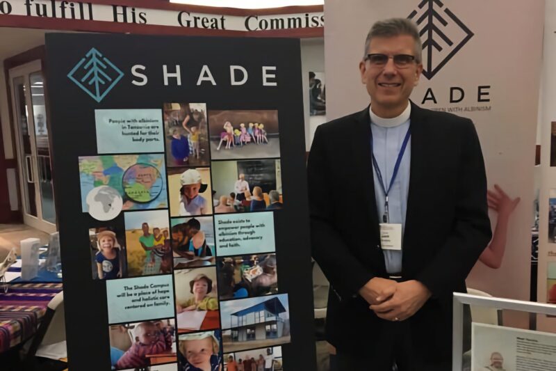 Man standing next to a SHADE organization display board.