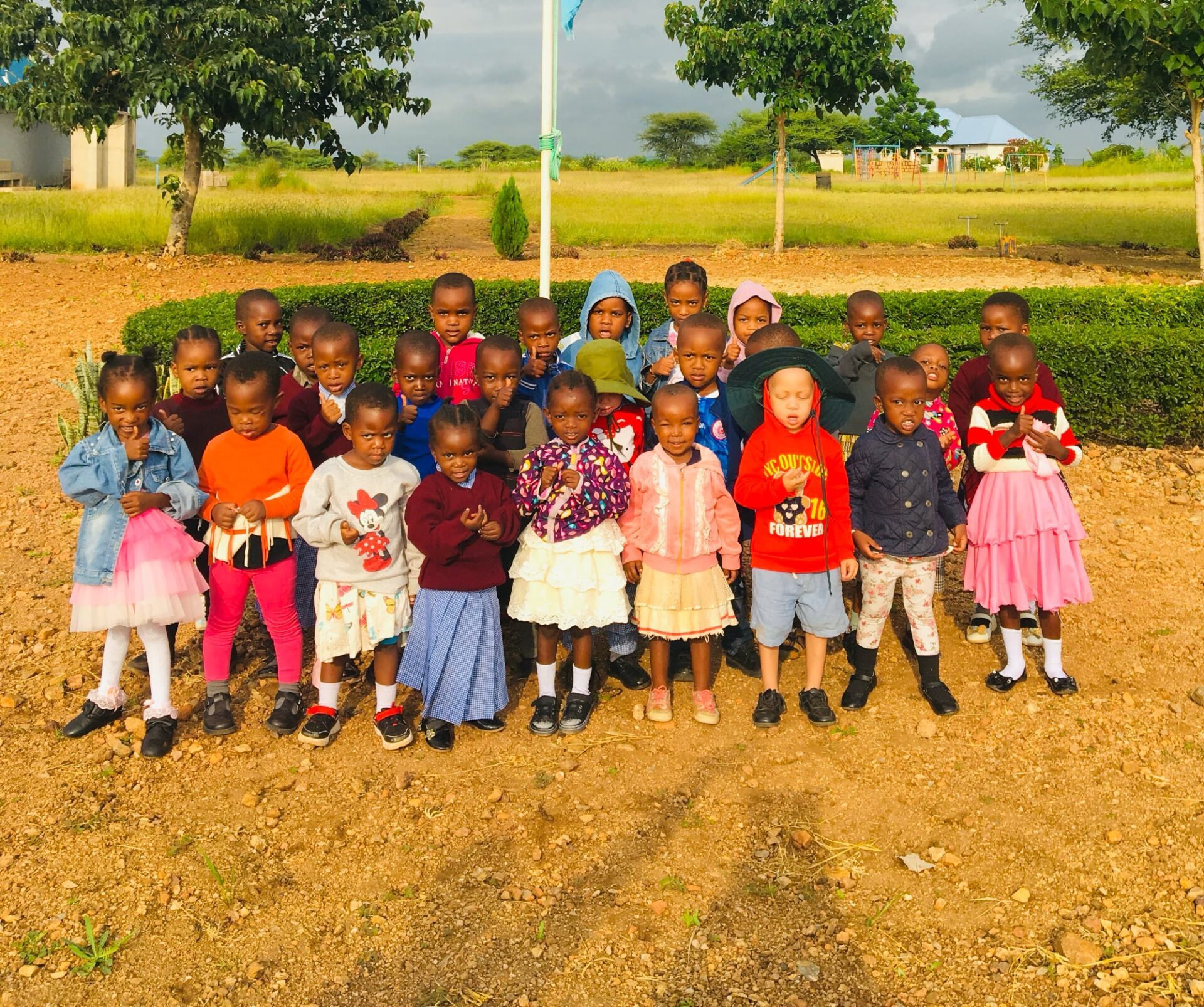 Photo of children standing in front of a flag pole